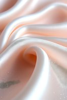Soft peach and white silk fabric with elegant folds and curves creating gentle waves and swirls, macro photography with selective focus and dreamy lighting effects.
