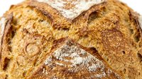 Freshly baked artisan bread loaf with crusty golden-brown exterior and flour dusting, perfect for bakery, food, and culinary design projects.