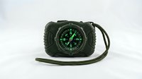 Tactical compass with green luminous dial and paracord survival bracelet, isolated on white background for outdoor adventure and emergency preparedness design use.