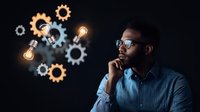 Thoughtful African American businessman with glasses contemplating innovative solutions, glowing lightbulbs and gears symbolize creative thinking process on dark background.