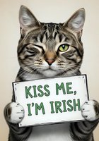 Tabby cat with striking green eyes holding a sign reading "Kiss Me, I'm Irish" against neutral background, suitable for St. Patrick's Day greeting cards, social media posts, and holiday marketing materials.