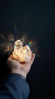 Hand holding luminous citrine crystal cluster radiating golden light and rainbow prisms against dark background. Suitable for wellness, spirituality, and alternative medicine content.