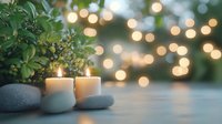Tranquil spa composition with burning candles, smooth stones and green plants against blurred bokeh lights background for wellness and relaxation atmosphere.