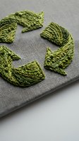 Green embroidery thread arranged in circular pattern on gray linen fabric showcasing traditional needlework and textile craft techniques for handmade projects.