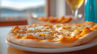 Fresh homemade pizza with melted mozzarella and sunny side up eggs on white plate, selective focus with blurred wine glass and window view background.
