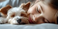 Young Caucasian woman with red lips sleeping peacefully next to her Yorkshire terrier puppy on white bedding, intimate bonding moment between pet owner and dog.