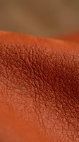 Macro shot of terracotta leather texture with detailed grain pattern and warm tones, suitable for backgrounds, design elements, and material reference projects.