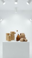 Sustainable packaging collection with wooden containers, amber glass bottles and cardboard boxes on white table in modern minimalist studio setting.