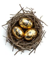 Three golden metallic eggs nestled in natural brown twig nest on white isolated background, luxury Easter or investment concept composition.