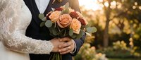 Newlywed couple holding peach rose wedding bouquet during golden hour ceremony celebration with romantic sunset lighting and elegant lace bridal gown details.