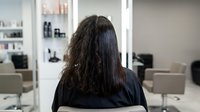 Hair transformation before and after straightening treatment at professional salon showing dramatic change from curly to sleek straight hair.