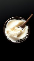 Vanilla ice cream scoops in rustic wooden bowl with wooden spoon on black background, isolated for food photography, dessert menus, and culinary design projects.