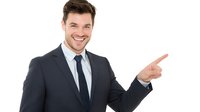 Confident Caucasian businessman in dark suit pointing to side with cheerful expression, presenting invisible product or idea on white background.