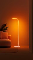 Modern minimalist floor lamp emitting warm orange light in cozy living room setting with sofa and palm plant, creating atmospheric ambient lighting effect.