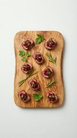 Gourmet appetizers with cranberry sauce on wooden cutting board garnished with fresh herbs for holiday entertaining and festive dining occasions.