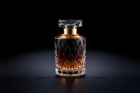 Crystal glass decanter with amber liquid on black background, dramatic lighting highlights luxurious cut pattern and metallic cap, creating elegant mood.