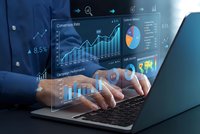 Business professional analyzing financial data on laptop with holographic charts and graphs displaying analytics dashboard for corporate performance monitoring.