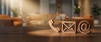 Wooden contact icons phone email at symbol on desk in modern office interior with warm sunlight for business communication concept.
