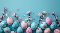 Decorated Easter eggs in pastel pink and turquoise with spring cherry blossom branches on blue background, festive holiday composition for spring celebration.