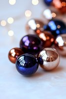 Shiny navy blue and copper Christmas ornaments with soft bokeh lights in background, creating festive holiday atmosphere on white surface.