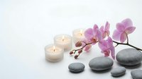 Spa wellness scene with purple orchid flowers, burning candles and smooth massage stones on white background for relaxation and beauty treatments.