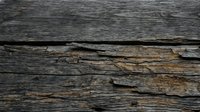 Weathered wooden surface with deep cracks and layers of aged timber showing natural decay and texture. Suitable for backgrounds, design elements, and rustic projects.