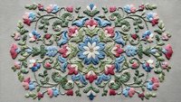 Intricate floral embroidery with colorful roses and blue flowers on fabric, featuring ornate decorative stitching and traditional needlework craftsmanship.
