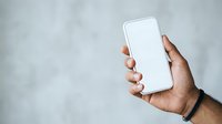 Male hand holding smartphone with blank white screen against gray textured background. Suitable for app mockups, technology marketing, and digital communication concepts.