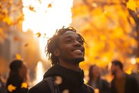 Young African American man smiling with genuine joy outdoors during golden hour sunset, autumn leaves creating warm bokeh background, expressing happiness and optimism.
