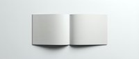 Open blank white book or magazine mockup with empty pages spread flat on light gray surface for branding and design presentation projects.