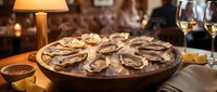 Fresh oysters on ice platter with wine glasses in elegant restaurant setting, perfect for seafood dining and culinary presentations.