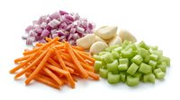 Fresh chopped vegetables including diced red onion, julienned carrots, minced garlic and celery on white background for cooking and meal preparation.