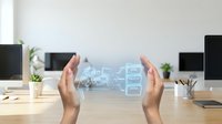Hands protecting holographic digital interface with data analytics charts and graphs in modern office workspace for business technology and cybersecurity concepts.