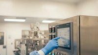 Healthcare professional operating medical equipment control panel in modern hospital laboratory with blue gloves for sterile procedure and patient safety.