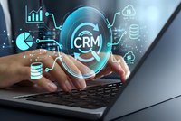 Businessman hands typing on laptop with glowing CRM customer relationship management system interface and digital business analytics icons.