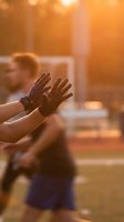 Hands raised in warm golden sunlight with blurred person in background creating atmospheric bokeh effect for wellness and positivity concepts.