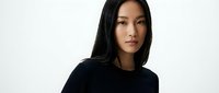 Young Asian woman with long black hair wearing black top against white background for portrait photography and commercial use.