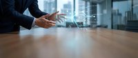 Businessman hands gesturing over holographic data visualization on wooden desk in modern office. Digital technology interface for business analytics and presentations.
