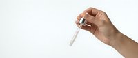Hand holding glass test tube with clear liquid for laboratory research and scientific experiments on white background.
