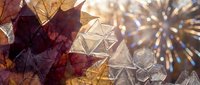 Autumn leaves with crystal glass geometric ornaments and sparkling bokeh lights creating festive holiday decoration background for seasonal celebrations.
