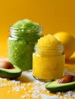 Colorful homemade body scrubs in glass jars with avocado and lemon on vibrant yellow background, natural skincare ingredients for spa treatments.