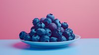 Fresh ripe blueberries piled on white ceramic plate against pink background, vibrant blue color and soft lighting create appetizing healthy food composition.