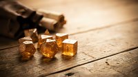 Amber translucent gaming dice set with numbers on rustic wooden table surface. Tabletop role-playing game accessories for fantasy adventures and entertainment.