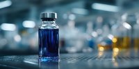 Blue liquid in glass vial on laboratory bench with blurred scientific equipment in background. Used in pharmaceutical research.