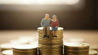 Senior couple sitting on stack of golden coins representing retirement savings and financial planning for elderly future security.