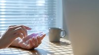 Female hands holding smartphone with glowing digital particles and light effects. Modern technology concept for mobile apps, communication and connectivity.