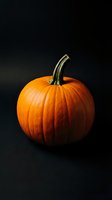 Fresh orange pumpkin with green stem on dark background for autumn harvest, Halloween decoration, and seasonal cooking projects.