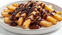 Crispy golden french fries drizzled with rich dark chocolate sauce on white ceramic plate, creating sweet and savory fusion cuisine combination.