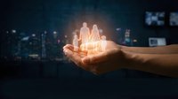 Hand holding glowing family silhouette against blurred city night background. Concept of protection, care, insurance and family security services.