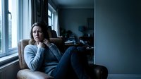 Thoughtful middle-aged Caucasian woman sitting by window in cozy armchair, contemplating life decisions in quiet home interior for mental health concepts.